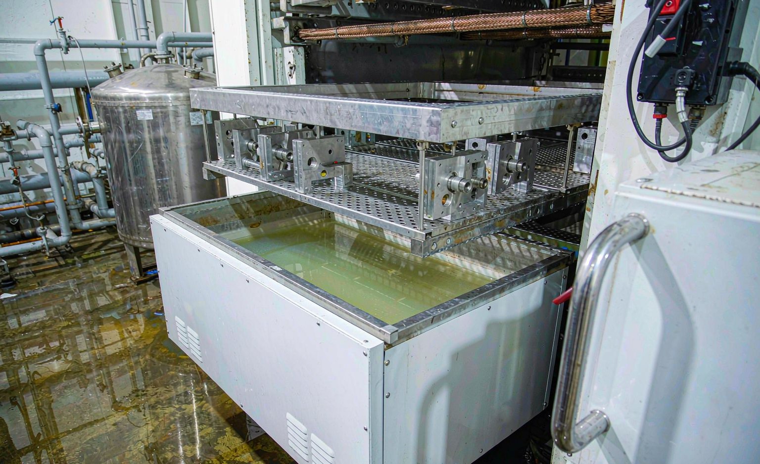 Aluminium anodizing line with parts loaded on titanium racks entering a tank